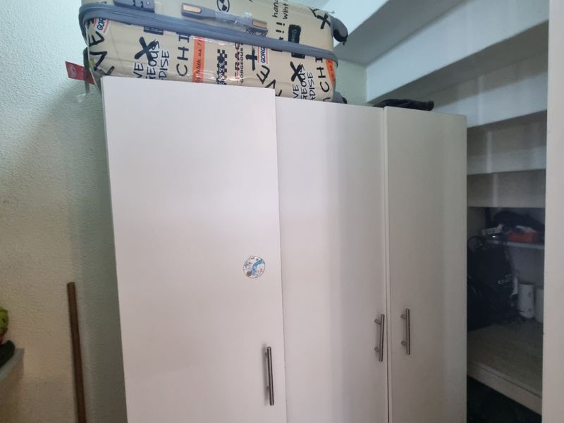 A utility storage area featuring built-in white cabinetry and open shelving for organized household storage.
