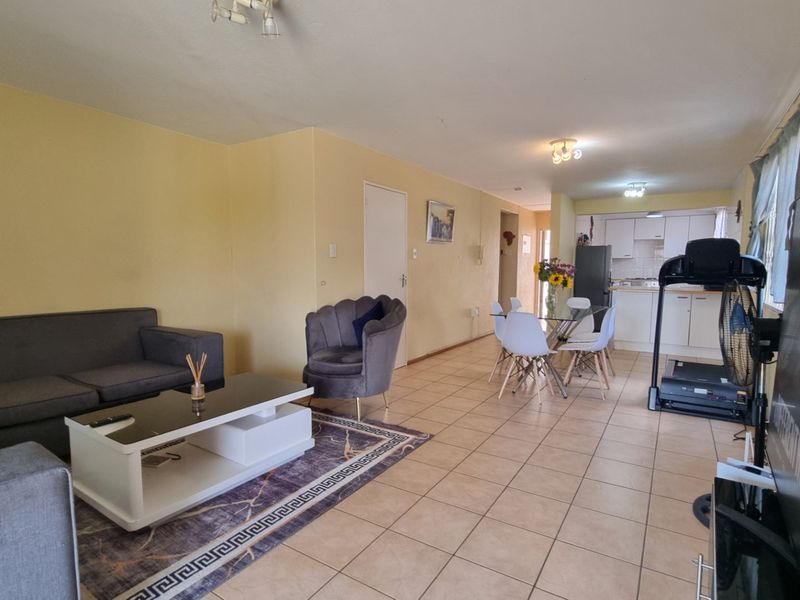 Open-plan living and dining area featuring tiled flooring and a connected kitchen space with built-in cabinetry.
