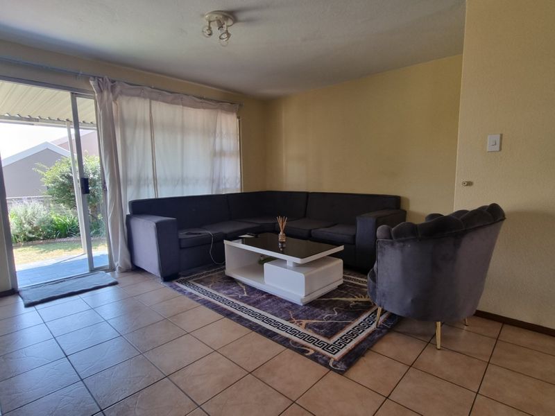 A living room featuring tiled flooring and a sliding glass door providing access to the outdoor area.