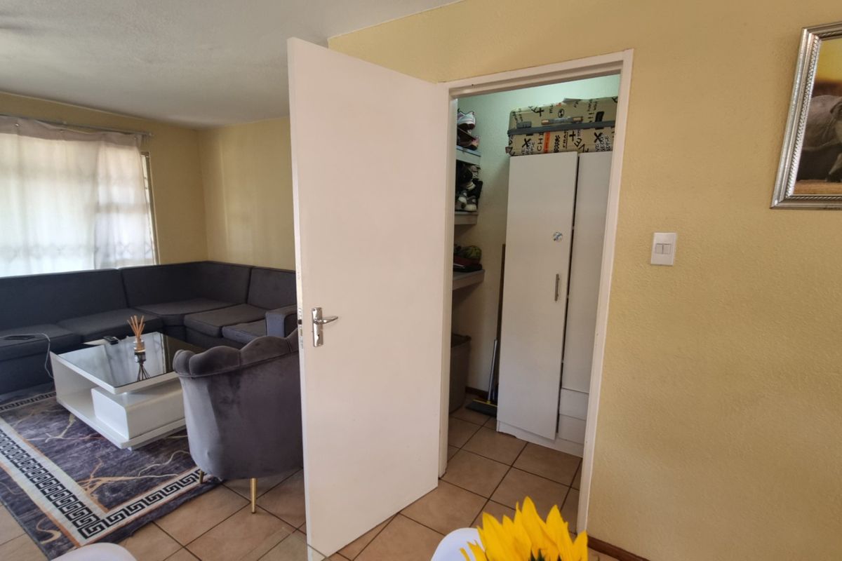 A living room area featuring tiled flooring and an adjacent built-in storage space with a door.