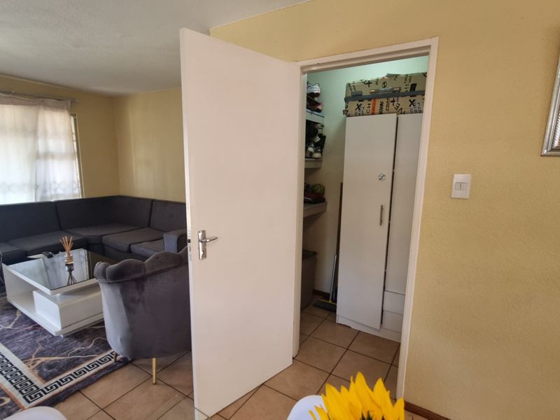 A living room area featuring tiled flooring and an adjacent built-in storage space with a door.