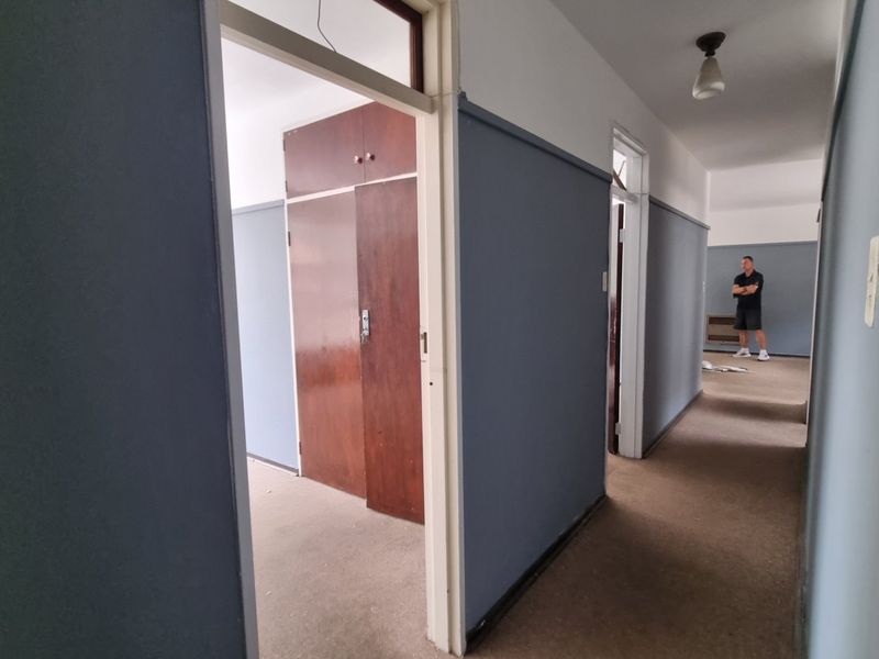A spacious hallway featuring built-in wooden cupboards and carpeted flooring, providing access to multiple rooms within the apartment.