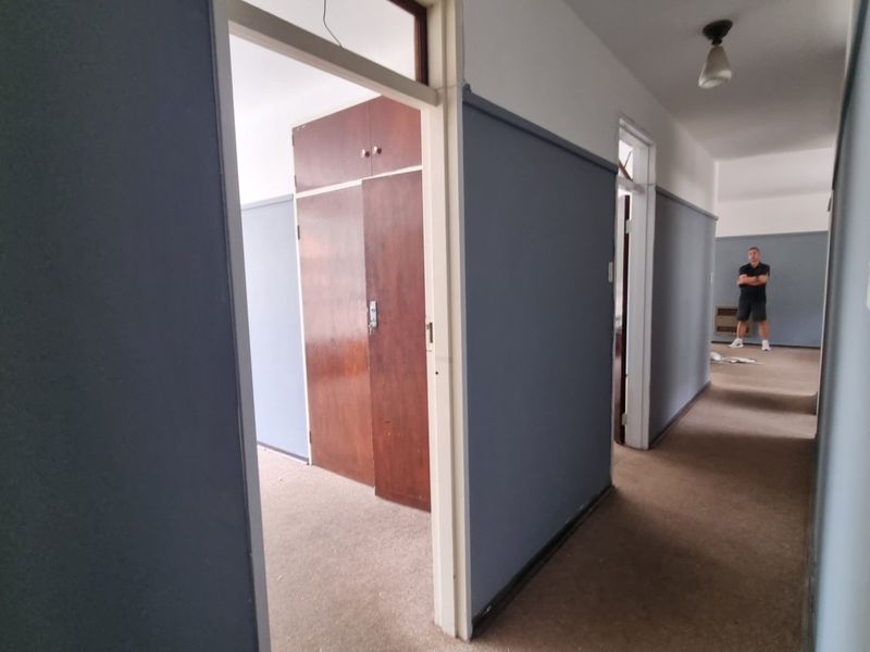 A spacious hallway featuring built-in cupboards and carpeted flooring, providing access to adjacent rooms within the apartment.