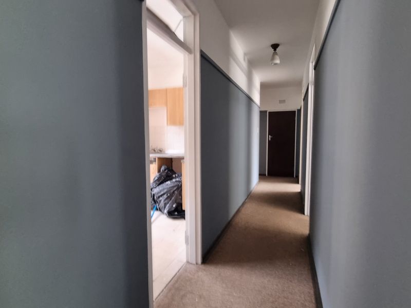A functional hallway connecting multiple rooms, featuring neutral wall paint, carpeted flooring, and access to adjacent living spaces.