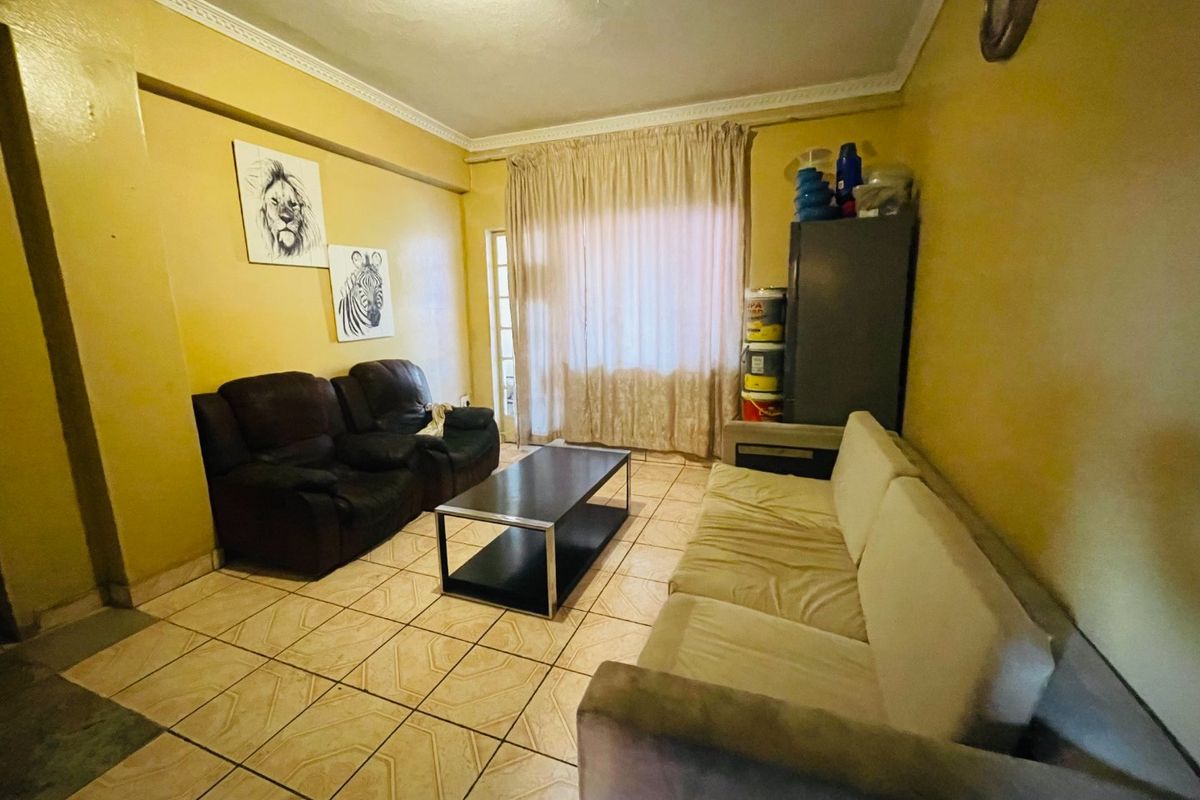 A living room featuring ceramic floor tiles, decorative ceiling cornicing, and a sliding glass door providing access to the exterior.