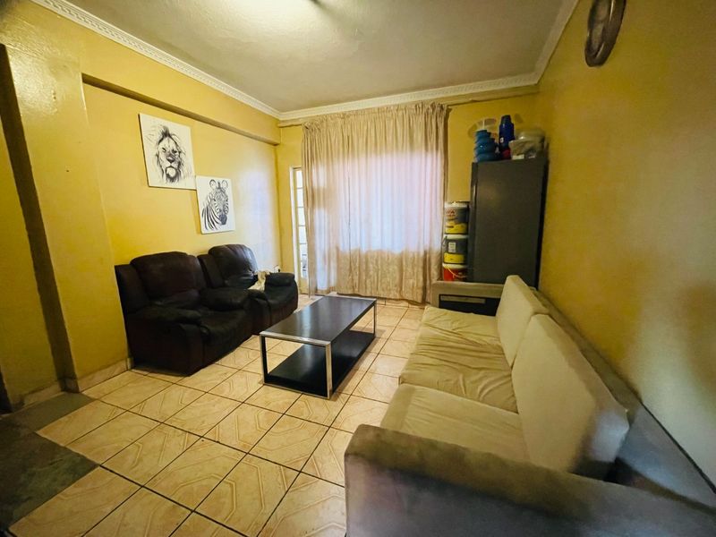 A living room featuring ceramic floor tiles, decorative ceiling cornicing, and a sliding glass door providing access to the exterior.