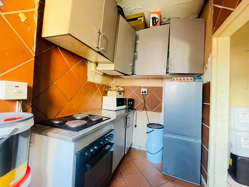 A compact kitchen featuring built-in cabinetry, an electric stove, and oven, requiring significant renovation and cosmetic updates to improve its overall condition and functionality.
