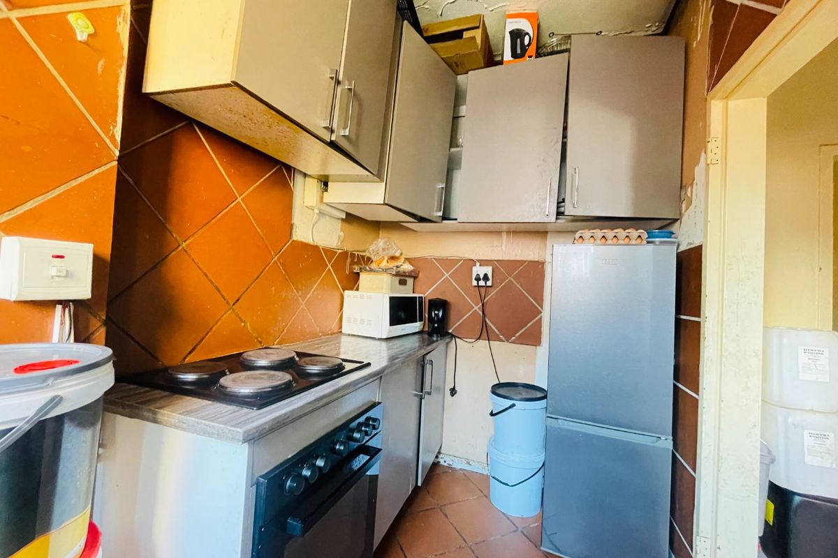 A compact kitchen featuring built-in cabinetry, an electric hob, and oven, requiring significant renovation and repair to the ceiling and wall finishes.