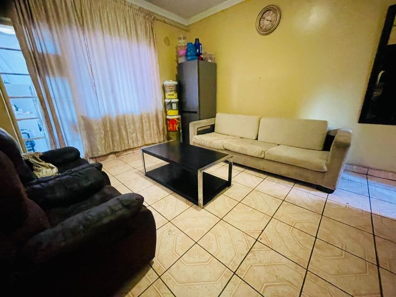 A living room area featuring tiled flooring and a sliding glass door, providing access to the exterior.