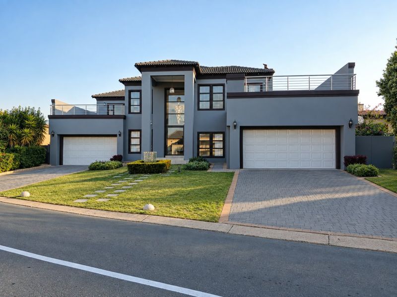 Modern double-story residence featuring a double garage, paved driveway, and upper-level balconies with clean architectural lines and well-maintained landscaping.