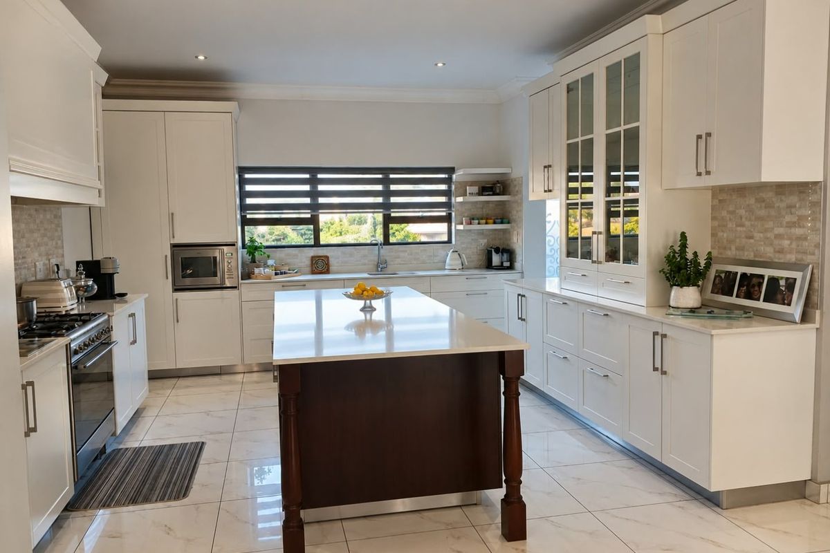 Modern, well-appointed kitchen featuring a central island, stone countertops, high-end built-in appliances, and elegant glass-fronted cabinetry with polished tiled flooring.