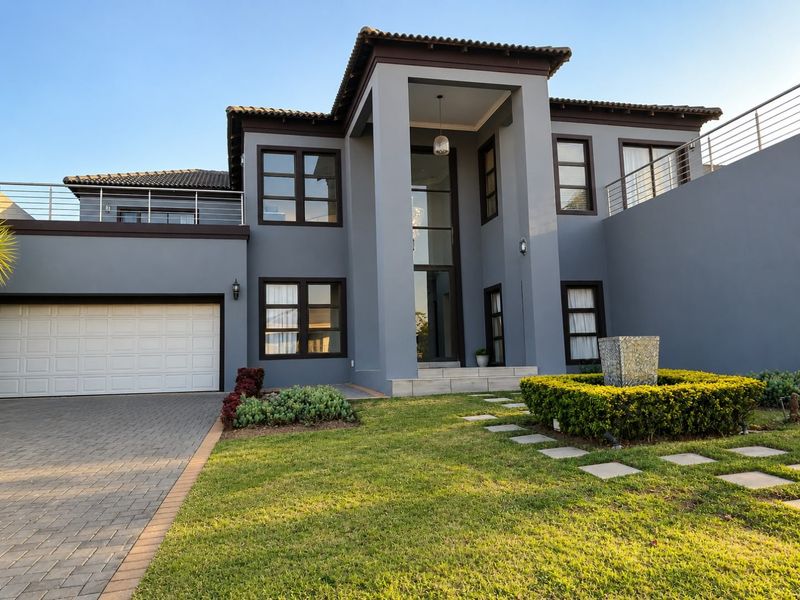Modern double-storey residence featuring a double garage, paved driveway, double volume entrance, and a well-maintained landscaped garden with a stone water feature.