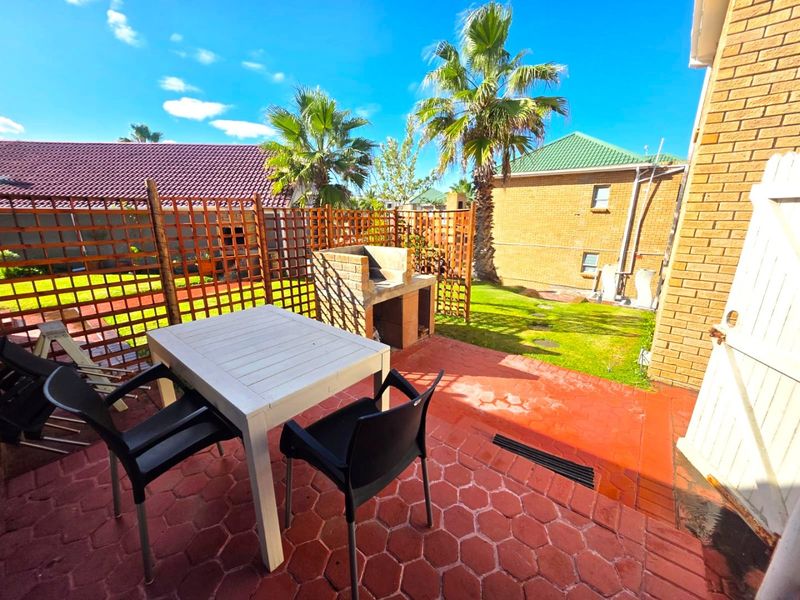 Outdoor patio area featuring a built-in brick braai, wooden privacy screening, and paved flooring, ideal for outdoor entertaining.