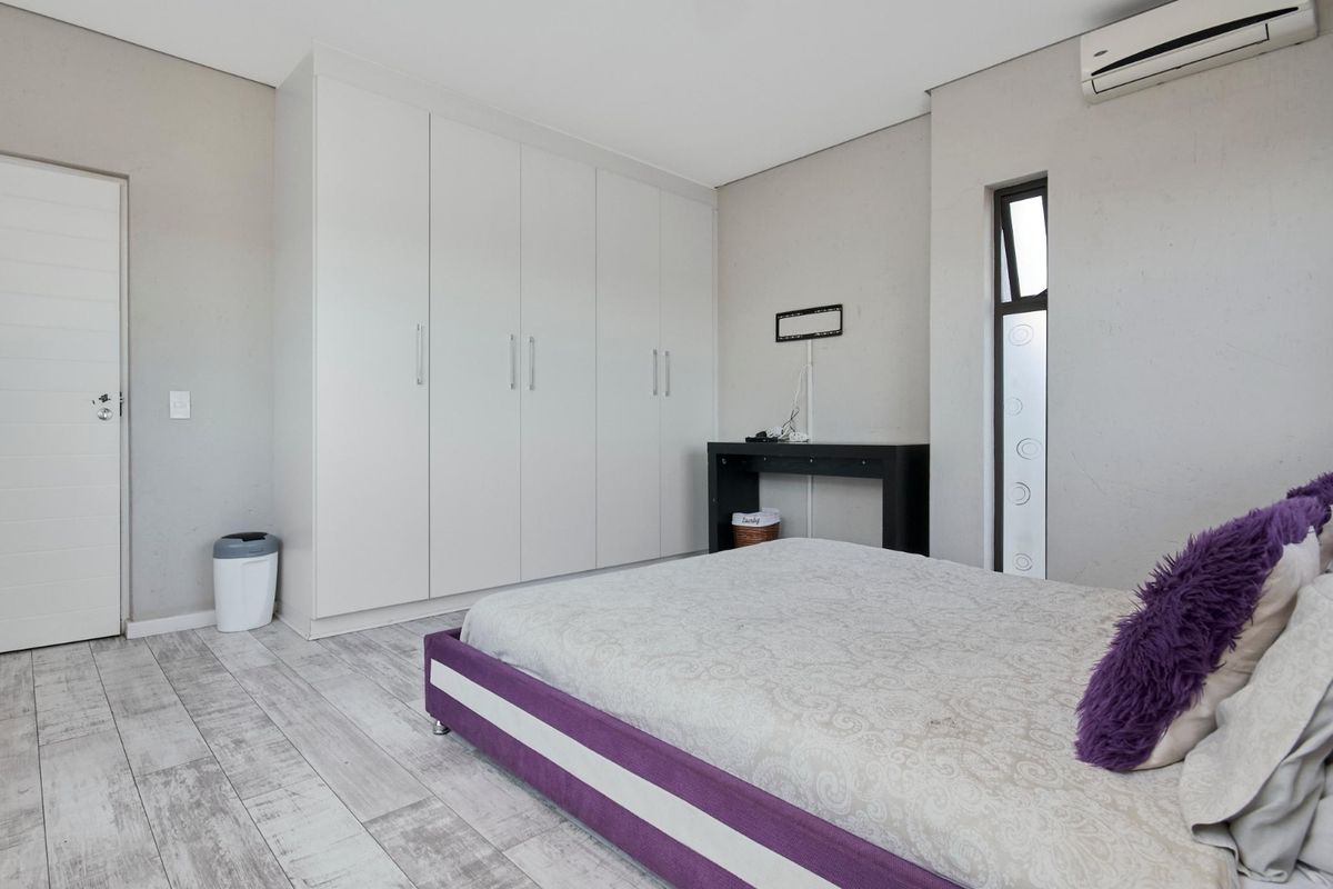 A well-maintained bedroom featuring built-in cupboards, tiled flooring, and a wall-mounted split-system air conditioner.