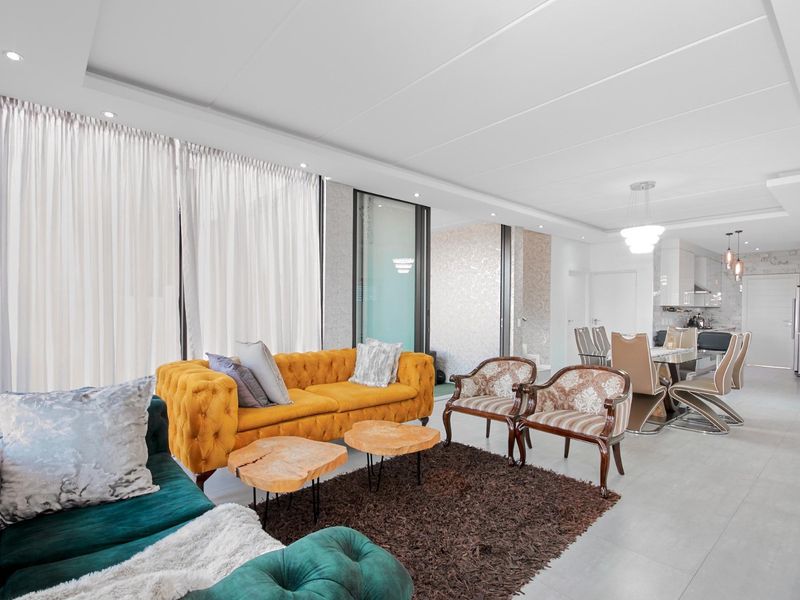 Spacious open-plan living and dining area featuring modern tiled floors, recessed ceiling lighting, and a seamless transition to a contemporary kitchen.