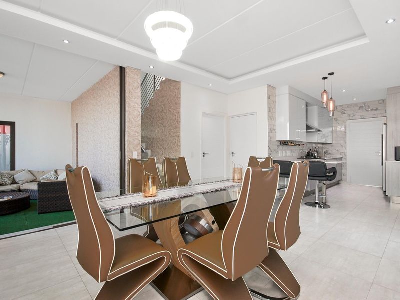 Modern open-plan living and dining area featuring tiled floors, recessed ceiling lighting, and a contemporary kitchen with marble-look finishes.