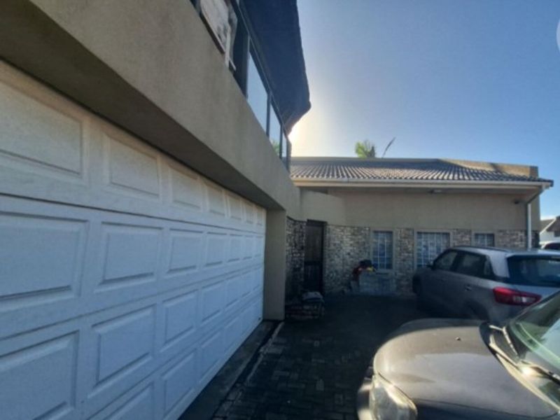 Front exterior view of the property featuring a garage door, stone cladding accents, and a paved driveway area.