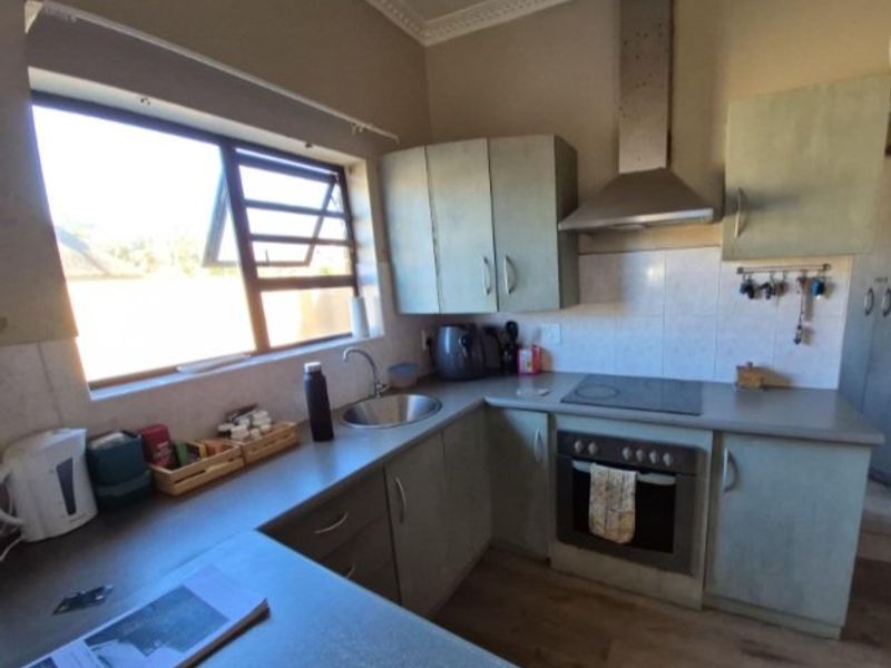 Functional kitchen featuring built-in cabinetry, laminate countertops, integrated electric hob and oven, stainless steel extractor fan, and tiled backsplash.