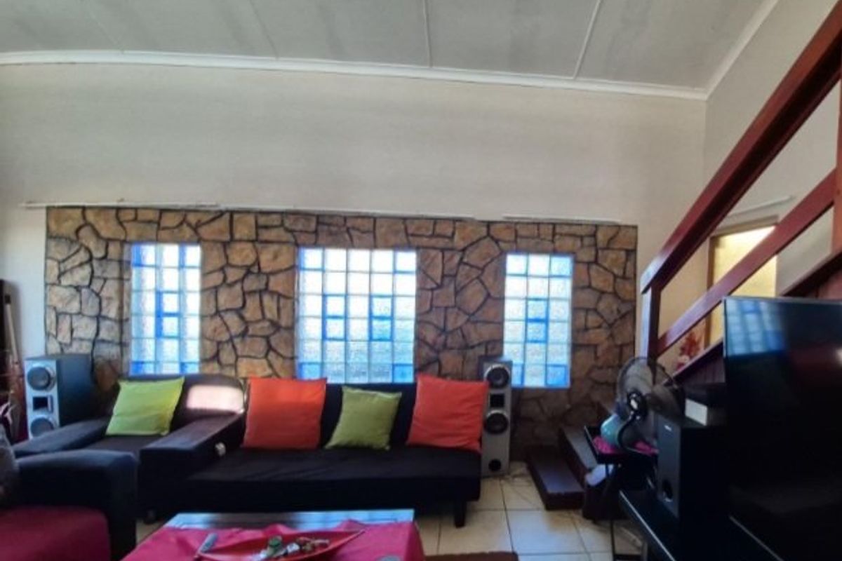 Living room featuring a stone accent wall with glass block windows, tiled flooring, and a wooden staircase leading to an upper level.