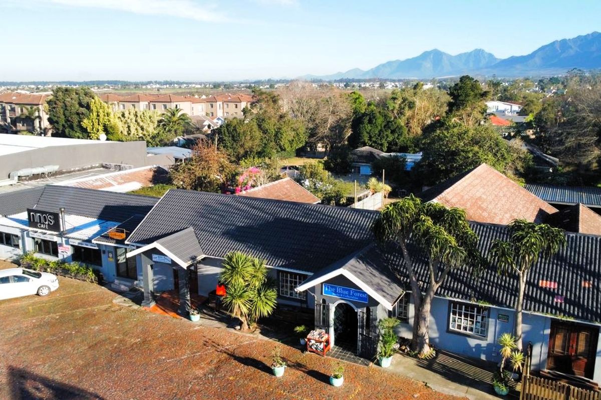 Aerial view of a commercial property complex featuring multiple units, tiled roofing, and paved parking areas in a suburban setting.