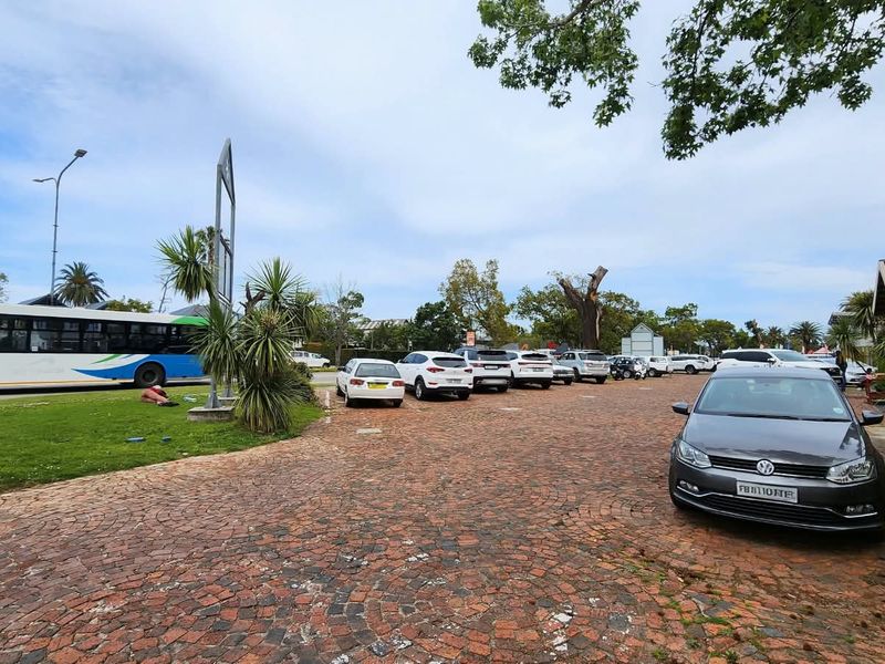 A commercial property exterior featuring a large cobblestone parking area and landscaped grounds.