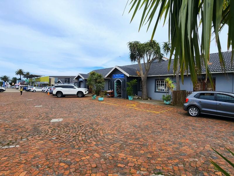 Front exterior view of a commercial property featuring a brick-paved parking area and a single-story building with a tiled roof.