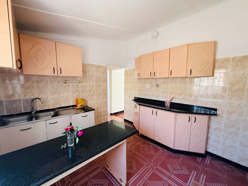 A functional kitchen featuring built-in cabinetry, granite countertops, a stainless steel sink, and tiled finishes throughout.