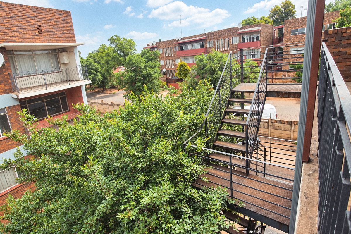 Exterior view of an apartment complex featuring a metal fire escape staircase, brick facade, and balcony access.