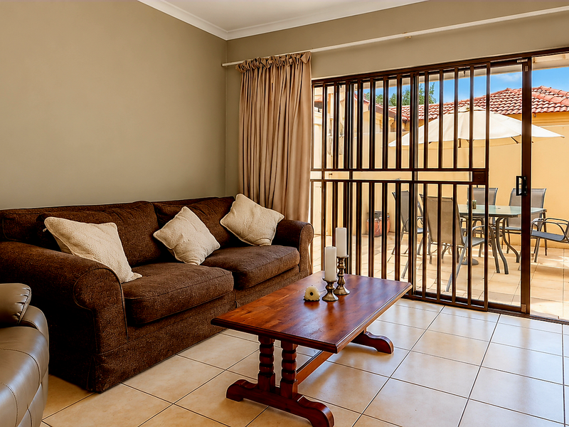 A living room featuring tiled flooring and a sliding glass door with a security gate, providing direct access to an outdoor patio area.
