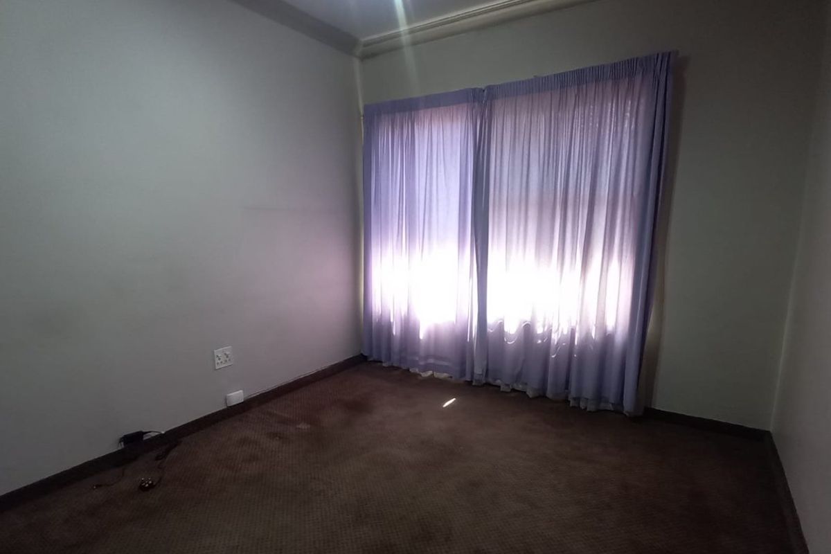An empty bedroom featuring carpeted flooring, a ceiling fan, and coved cornicing, offering a blank canvas for potential renovation or restyling.
