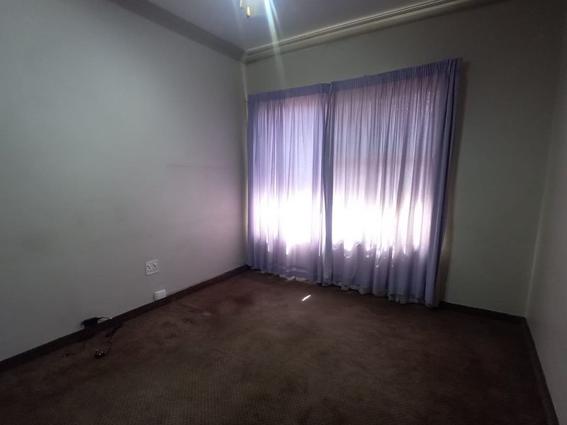 An empty bedroom featuring carpeted flooring, a ceiling fan, and coved cornicing, offering a blank canvas for potential renovation or restyling.