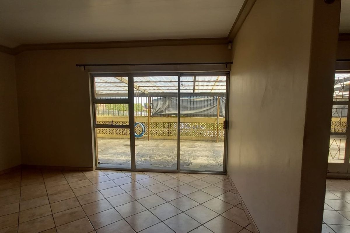 An empty living room featuring tiled flooring and a large sliding glass door providing access to an outdoor patio area.