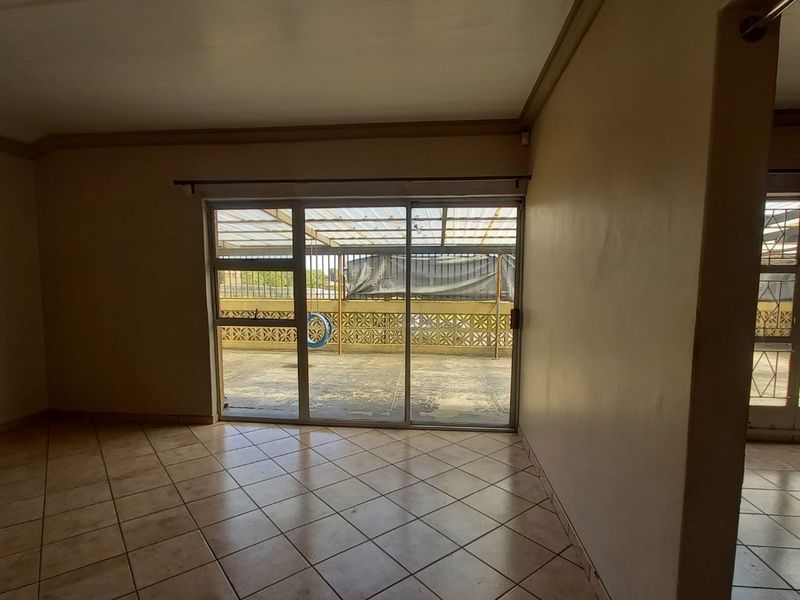 An empty living room featuring tiled flooring and a large sliding glass door providing access to an outdoor patio area.
