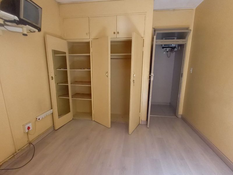An empty bedroom featuring built-in cupboards and light-toned laminate flooring, offering a blank canvas for potential interior updates.