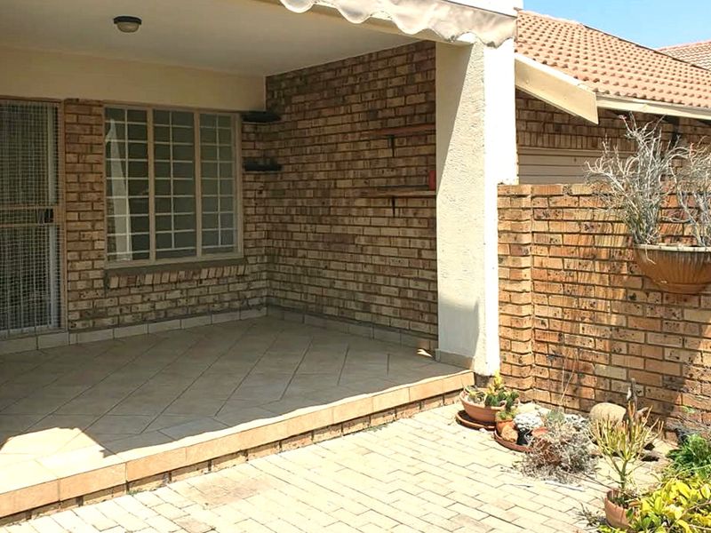 A covered patio area featuring brick walls, tiled flooring, and a retractable awning, providing a functional outdoor space for relaxation.