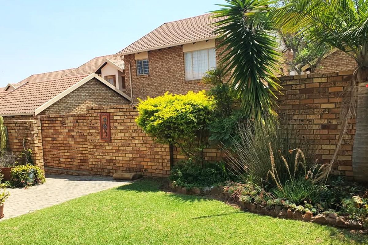 A private rear garden featuring a paved patio area, established landscaping, and a face brick boundary wall, providing a pleasant outdoor space.