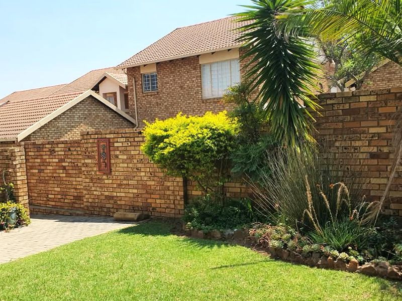 A private rear garden featuring a paved patio area, established landscaping, and a face brick boundary wall, providing a pleasant outdoor space.