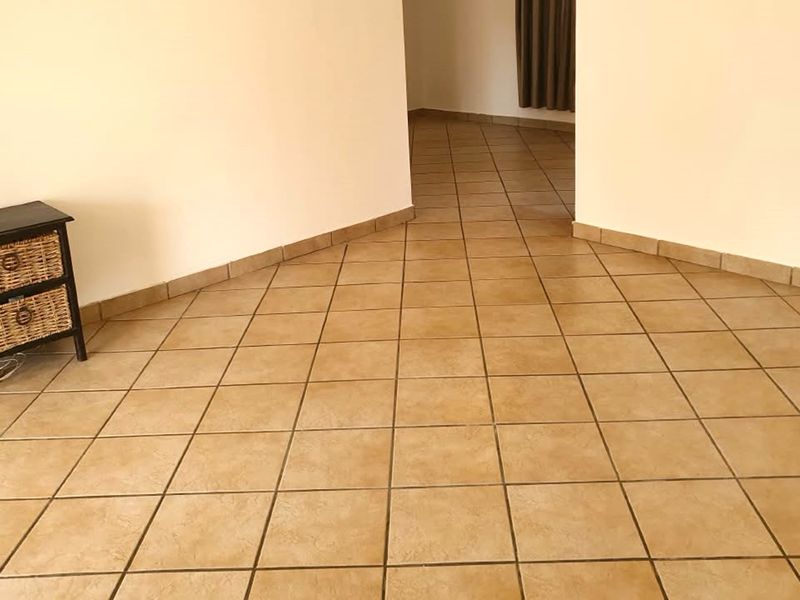 An empty living area featuring neutral tiled flooring and matching tiled skirting boards, providing a clean and versatile space.