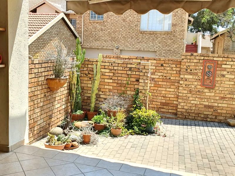 A private paved patio area featuring a brick boundary wall, built-in shelving, and a retractable awning, offering a low-maintenance outdoor space.
