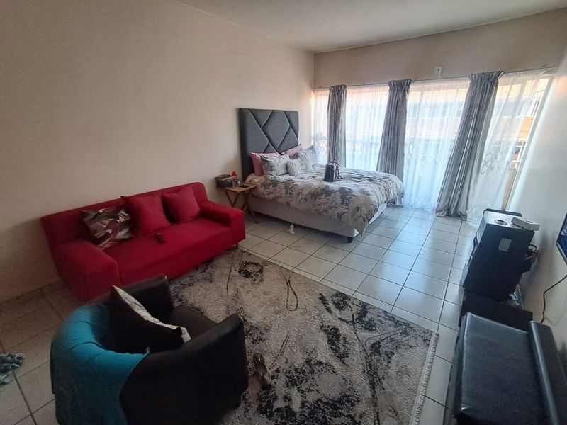 Open-plan studio apartment featuring tiled flooring and large sliding glass doors that provide access to the exterior, offering a functional living and sleeping space.