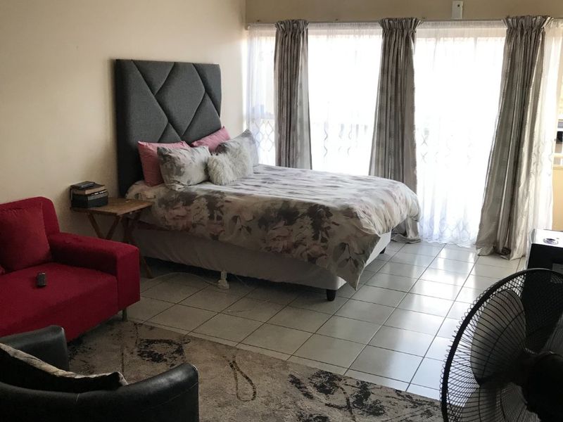 A bedroom featuring tiled flooring and a large sliding glass door that provides access to an outdoor area.