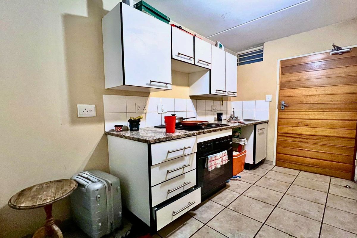 Compact kitchen featuring built-in cabinetry, a hob, oven, and tiled flooring, offering a functional layout with potential for modern updates.