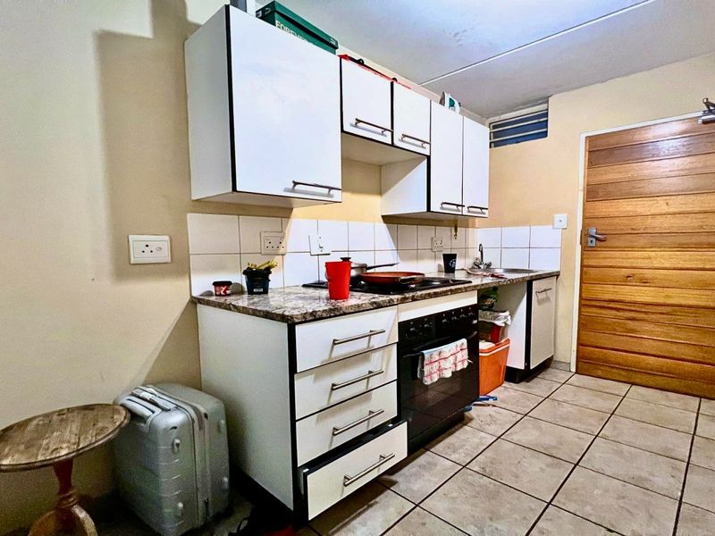 Compact kitchen featuring built-in cabinetry, a hob, oven, and tiled flooring, offering a functional layout with potential for modern updates.