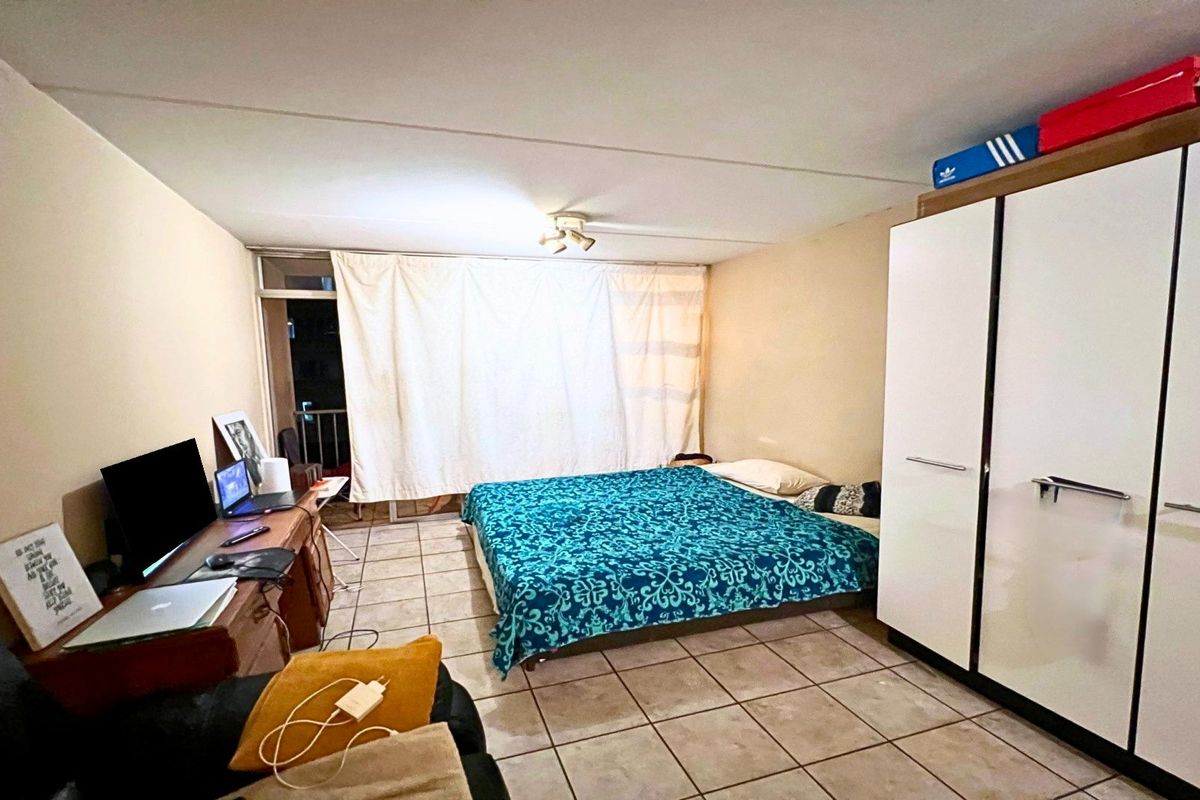 A bedroom featuring tiled flooring, a built-in wardrobe, and a sliding glass door providing access to an outdoor area.