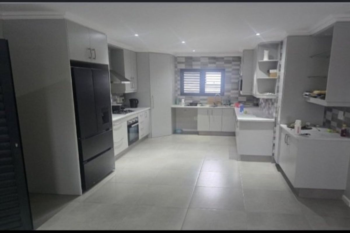 Modern kitchen featuring sleek cabinetry, stone countertops, integrated appliances, and tiled flooring with recessed lighting.