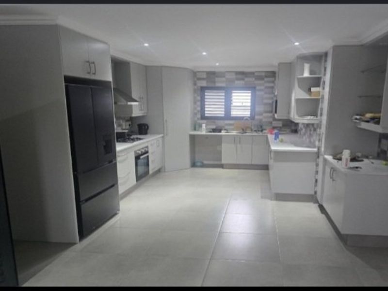 Modern kitchen featuring sleek cabinetry, stone countertops, integrated appliances, and tiled flooring with recessed lighting.