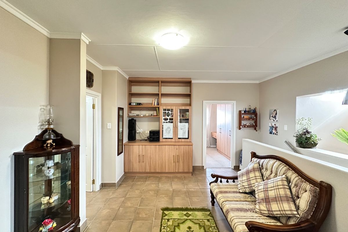 A living area featuring tiled flooring, built-in wooden cabinetry, and ceiling cornice detailing, providing a functional and neutral space.