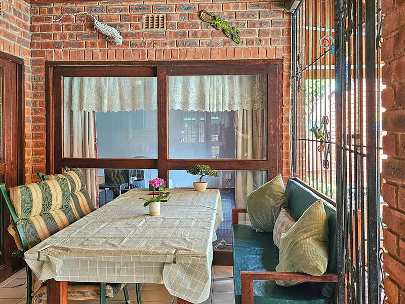 A covered patio area featuring exposed brick walls, tiled flooring, and sliding glass doors providing access to the interior living space.