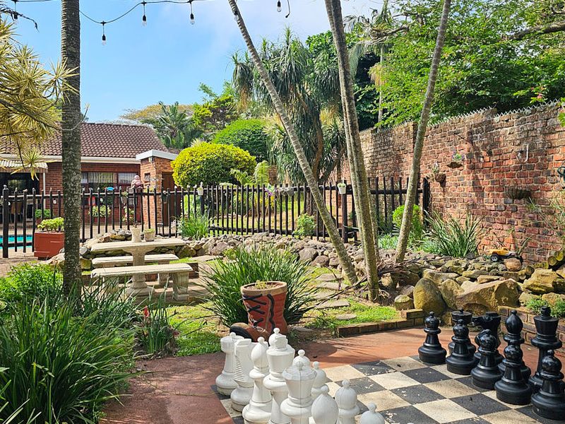 A landscaped garden area featuring a brick boundary wall, paved patio space, and a swimming pool, offering a private outdoor entertainment setting.