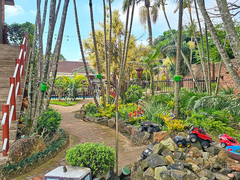 A lush, landscaped garden featuring a brick pathway, stone retaining walls, and an external staircase leading to the upper level of the property.